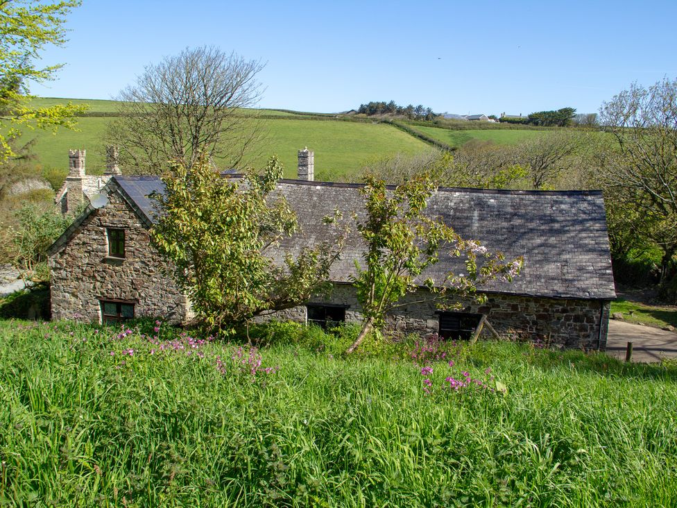 A house with trees and flowers in front at Carrows Stable Morwenstow