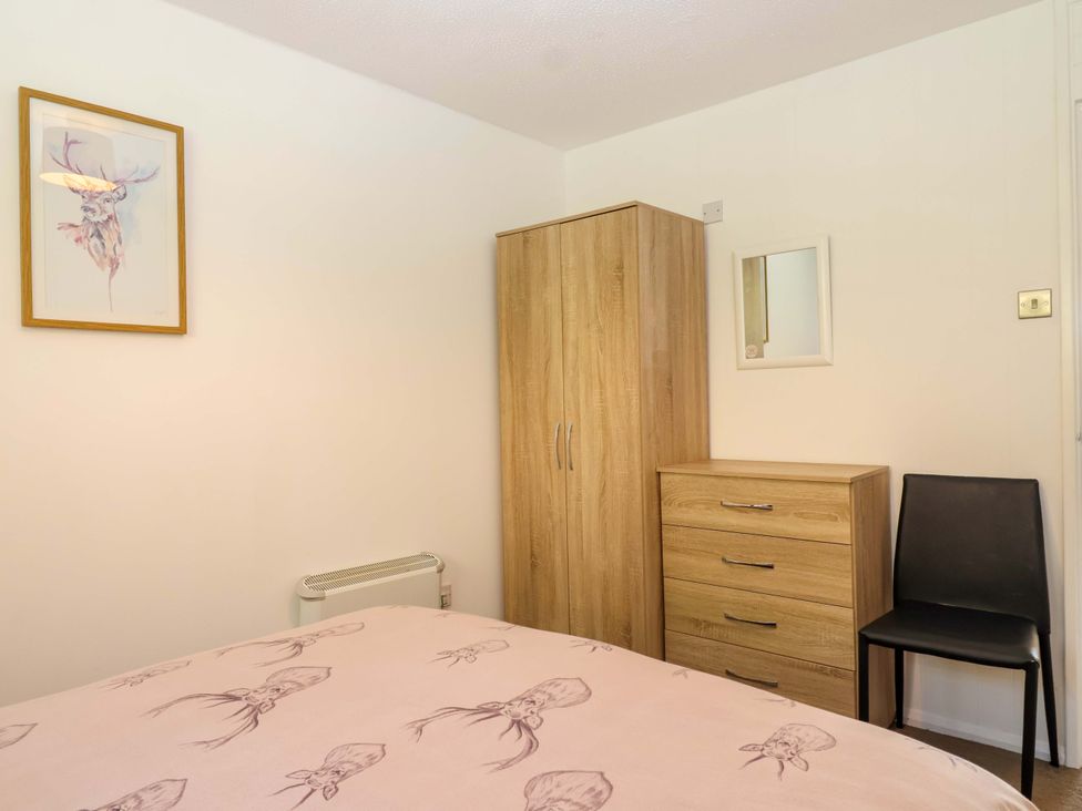 A bedroom with furniture including a wardrobe and chair at 13 Manorcombe Bungalows Honicombe Holiday Village near Gunnislake