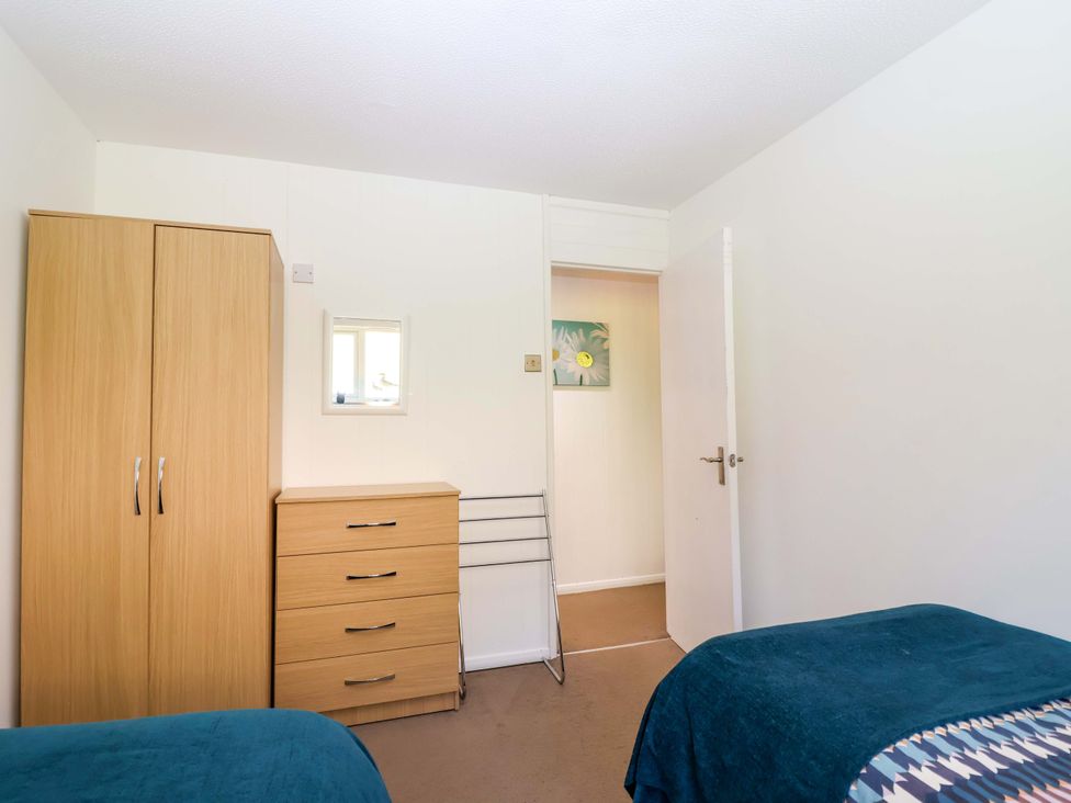 A bedroom with wardrobe, dresser, mirror and door at 13 Manorcombe Bungalows Honicombe Holiday Village near Gunnislake