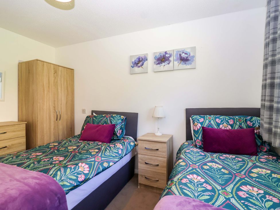 A bedroom with twin beds and a nightstand at 13 Manorcombe Bungalows Honicombe Holiday Village near Gunnislake