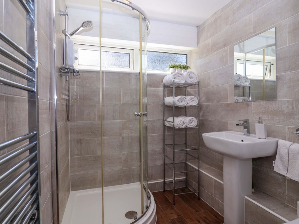 A bathroom with a shower, sink, and towel rack at 13 Manorcombe Bungalows Honicombe Holiday Village near Gunnislake