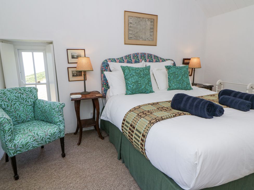 A bedroom with a bed and a chair at Dolwylan Cottage in Cwmtydu near New Quay