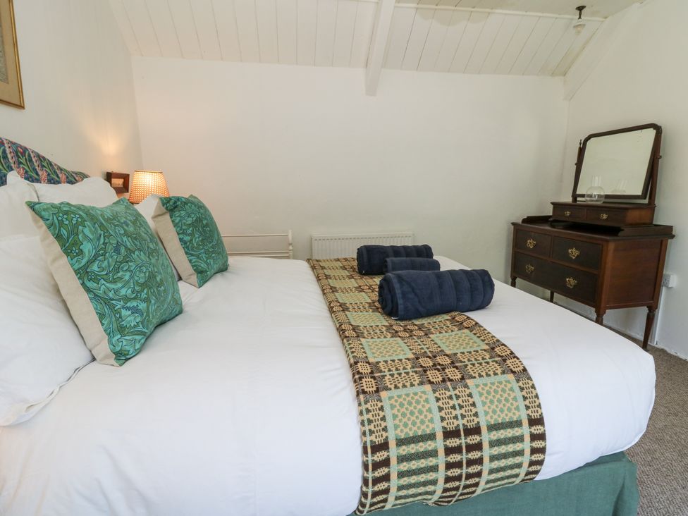 A bedroom with a bed and dresser at Dolwylan Cottage Cwmtydu near New Quay