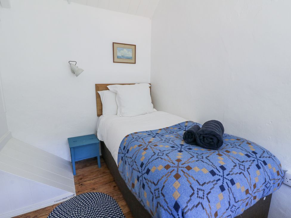A bedroom with a single bed and a nightstand at Dolwylan Cottage in Cwmtydu near New Quay