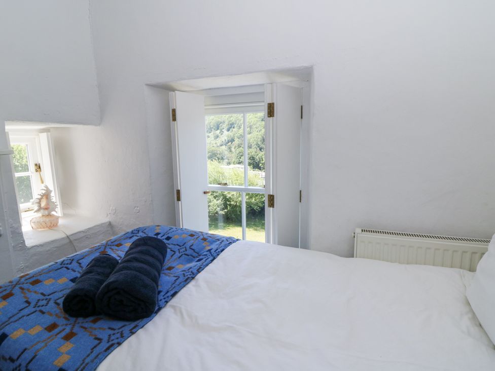 A bedroom with a bed and towels at Dolwylan Cottage in Cwmtydu near New Quay