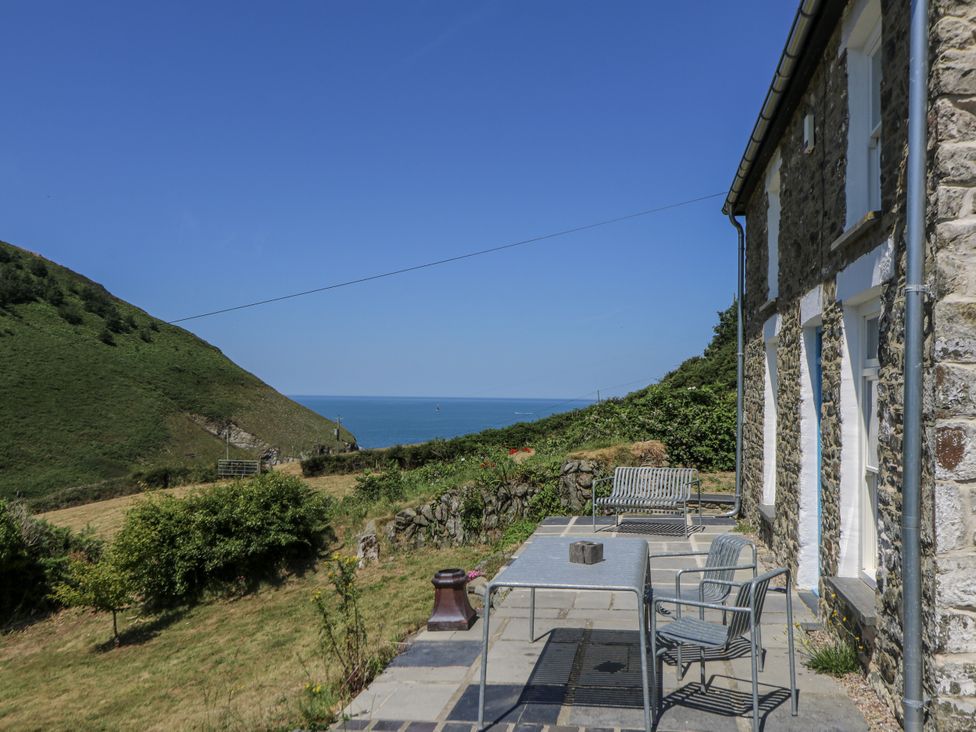 An outdoor area with a table and benches overlooking the sea at Dolwylan Cottage Cwmtydu near New Quay