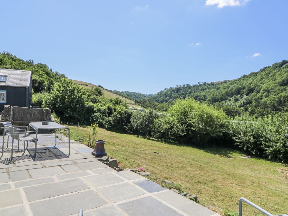 An outdoor area with a table and chairs overlooking a hill at Dolwylan Cottage Cwmtydu near New Quay