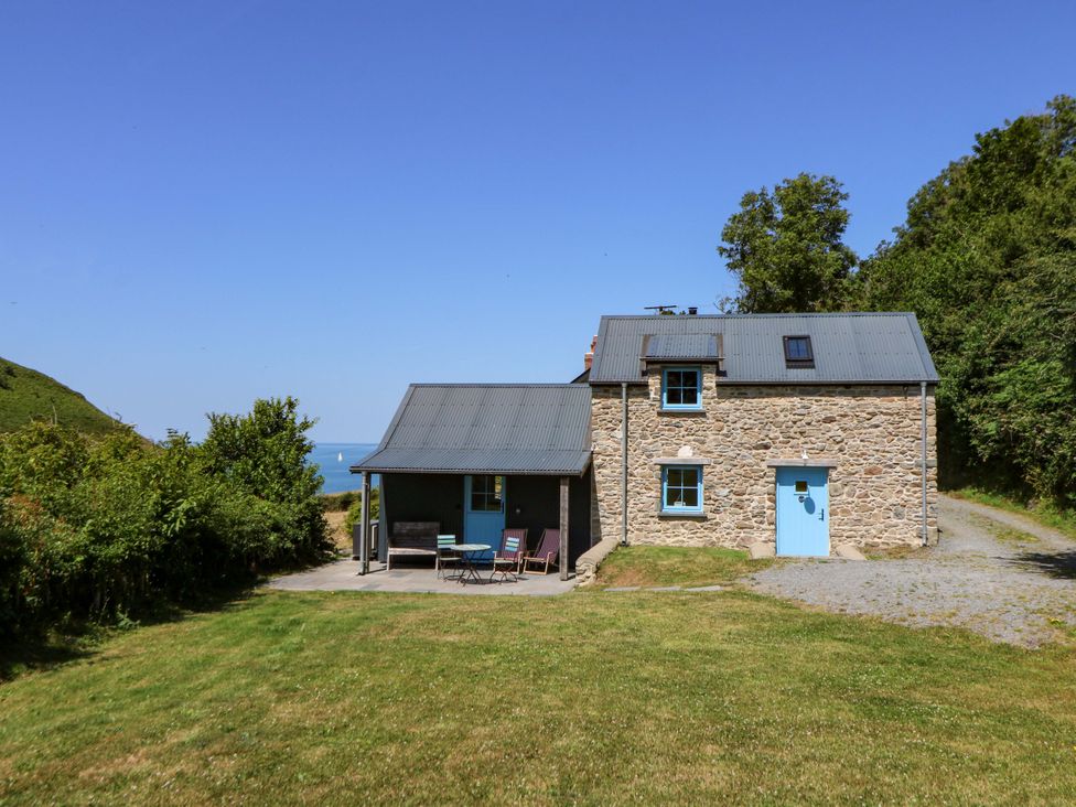 A house with a blue door and patio furniture at Dolwylan Barn Cwmtydu near New Quay