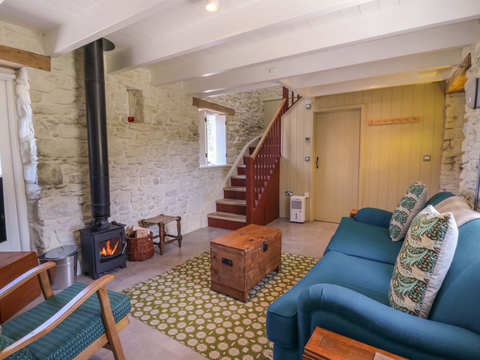 A living room with a stove and sofa at Dolwylan Barn in Cwmtydu near New Quay