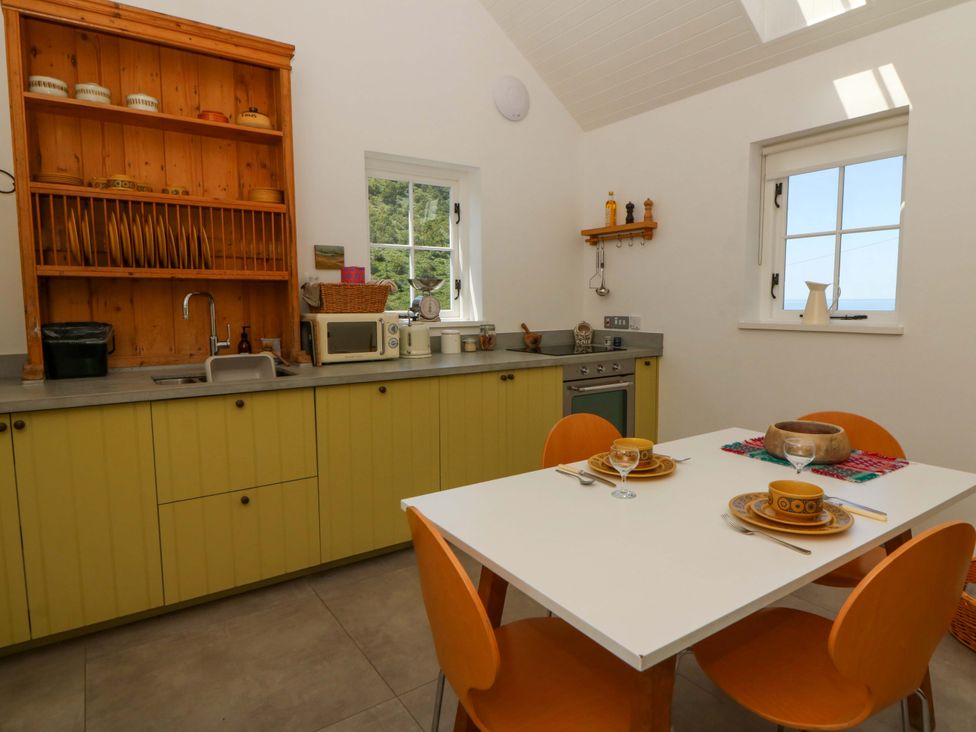 A kitchen with a table and chairs at Dolwylan Barn in Cwmtydu near New Quay