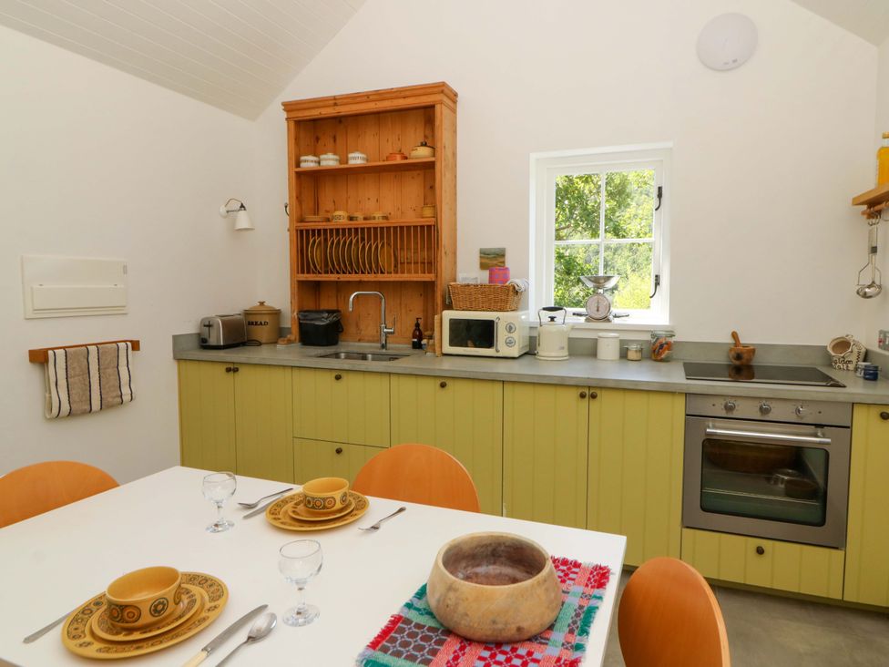 A kitchen with a table and chairs at Dolwylan Barn in Cwmtydu near New Quay