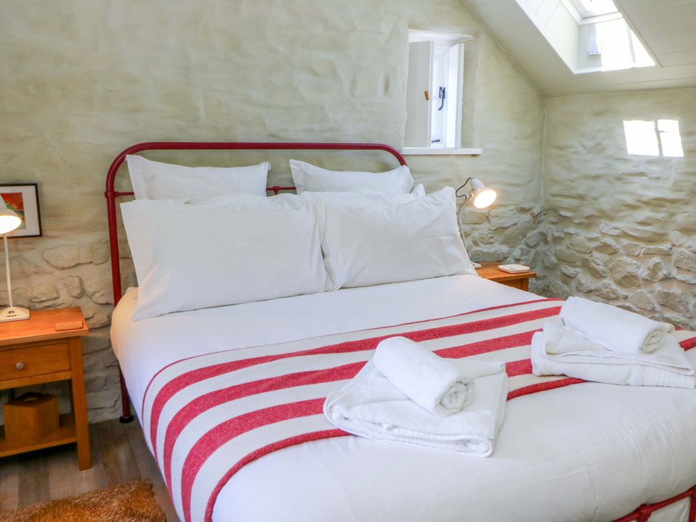 A bedroom with a bed and bedside table at Dolwylan Barn Cwmtydu near New Quay