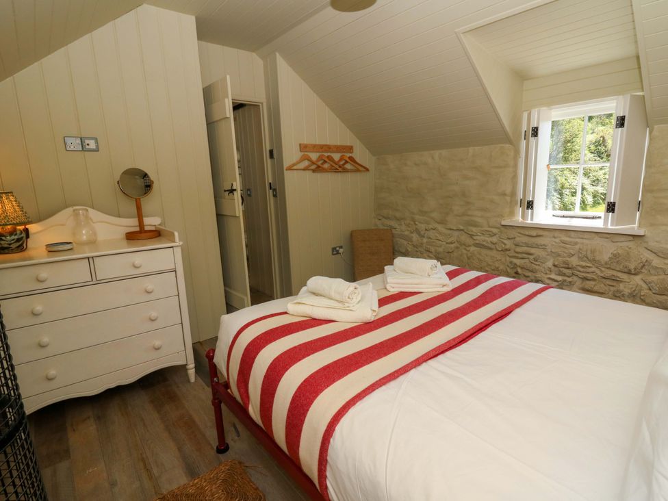 A bedroom with a bed and dresser at Dolwylan Barn in Cwmtydu near New Quay