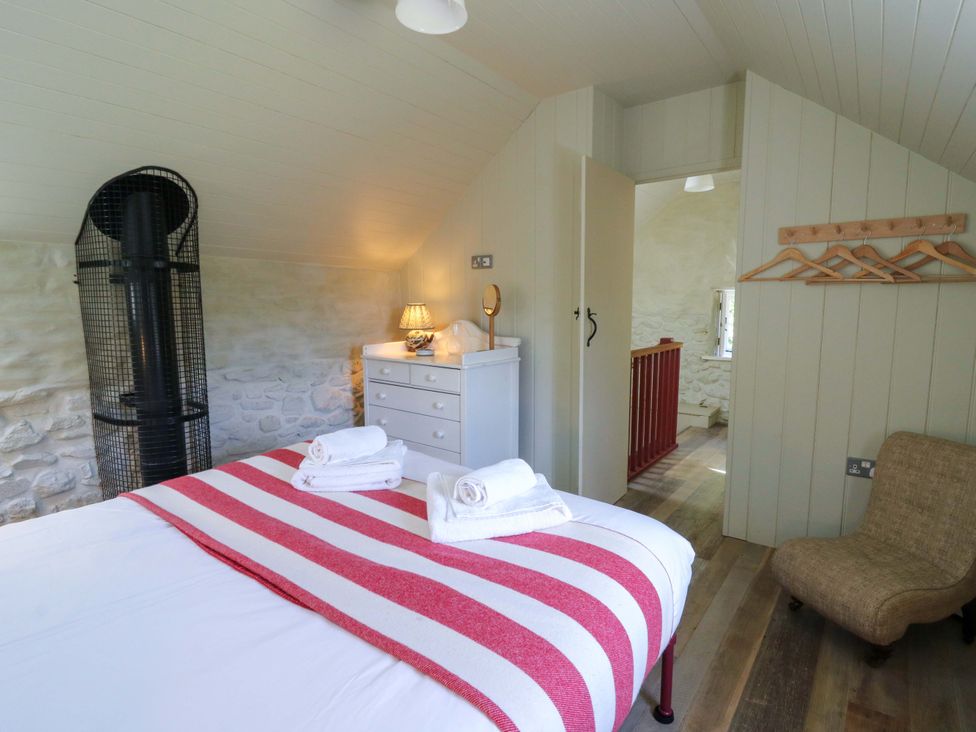 A bedroom with a bed and furniture at Dolwylan Barn in Cwmtydu near New Quay