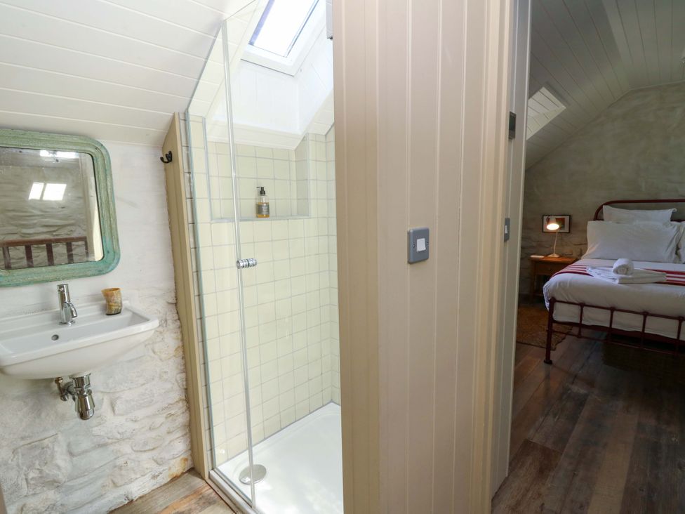 A bedroom with a bed and a shower area at Dolwylan Barn in Cwmtydu near New Quay