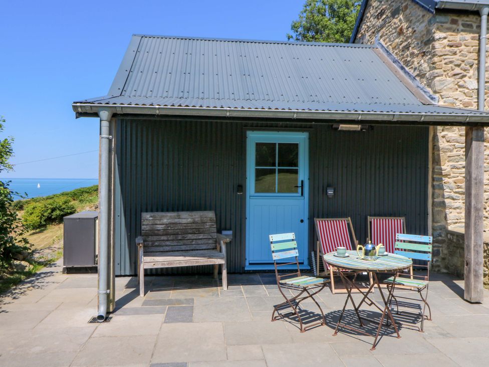 An outdoor seating area with a table and chairs at Dolwylan Barn Cwmtydu near New Quay