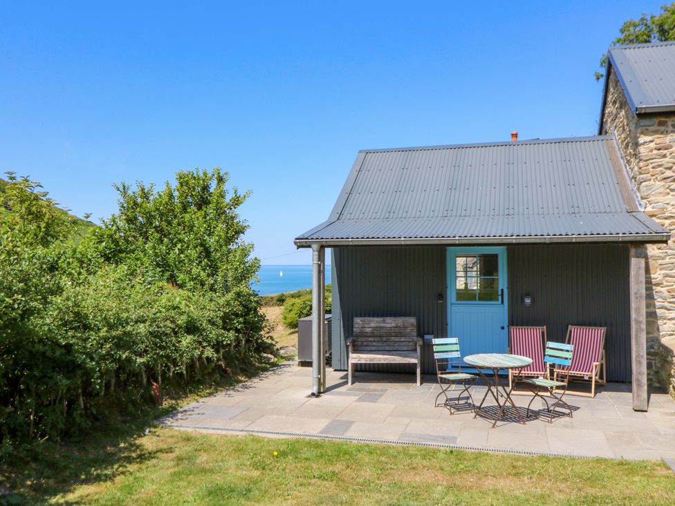 An outdoor area with a cottage, table and chairs at Dolwylan Barn Cwmtydu near New Quay