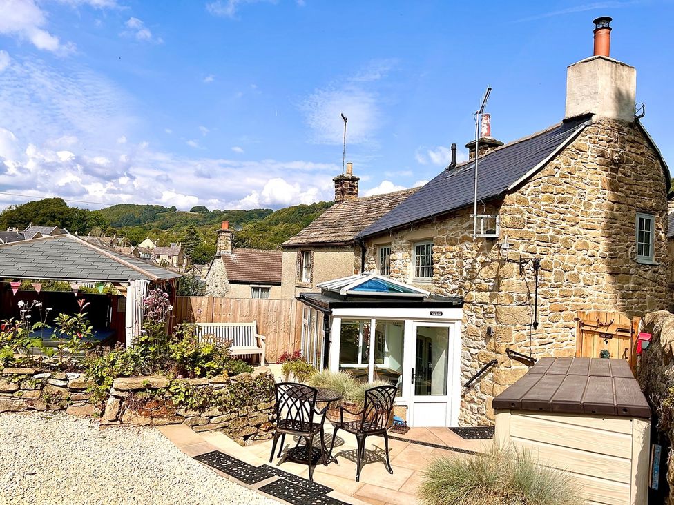 A stone cottage with outdoor seating area at Lydgate Cottage Eyam