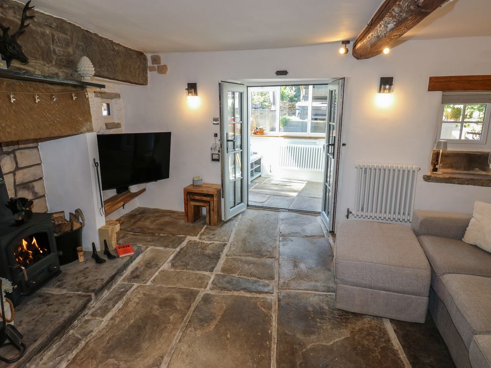 A living room with a fireplace and television at Lydgate Cottage in Eyam