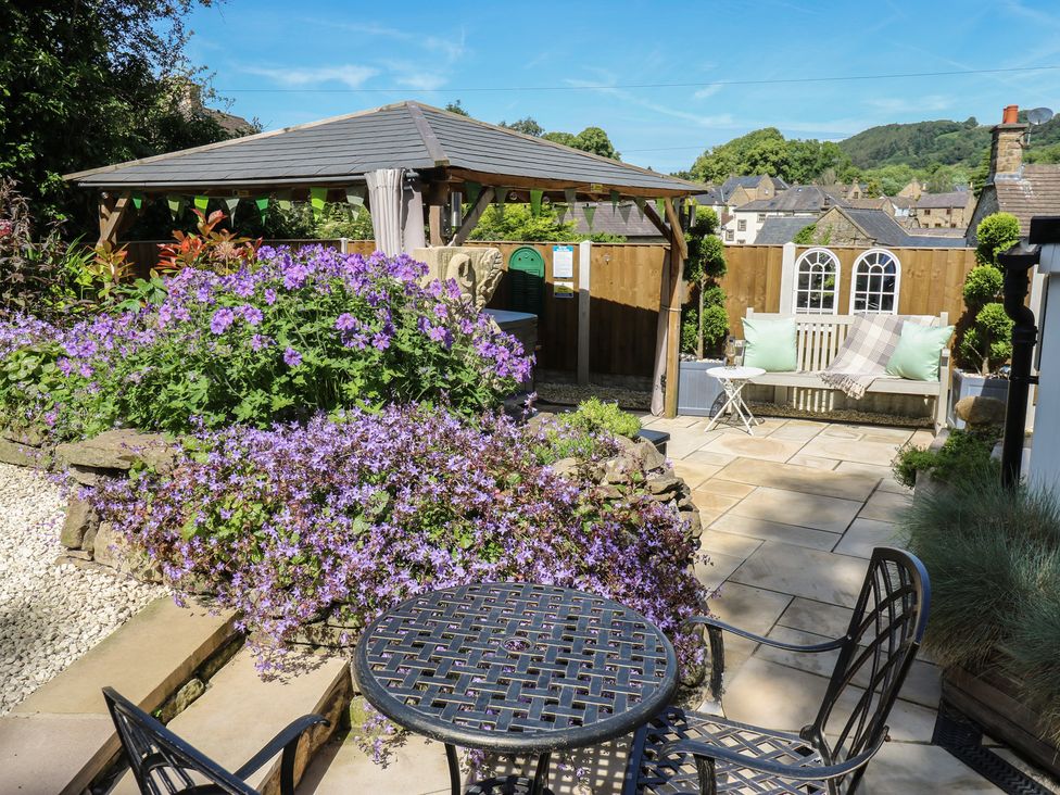 A garden with a gazebo, table, and flowers at Lydgate Cottage in Eyam