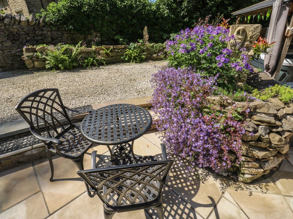 A garden with a table and chairs near flowers at Lydgate Cottage in Eyam