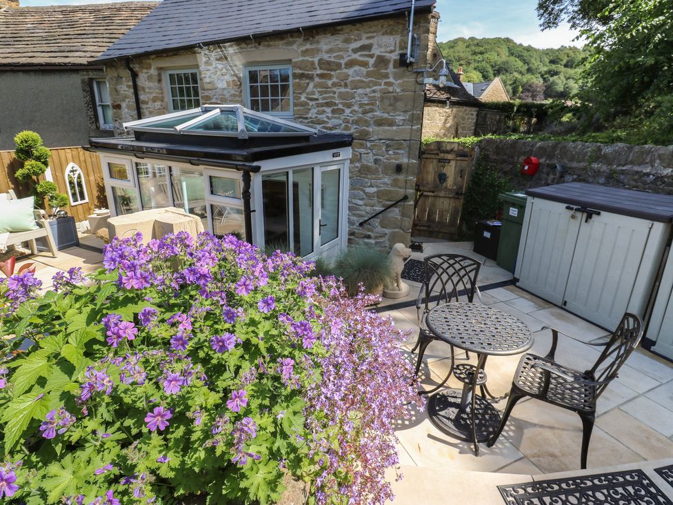 A garden with flowers and outdoor furniture at Lydgate Cottage in Eyam