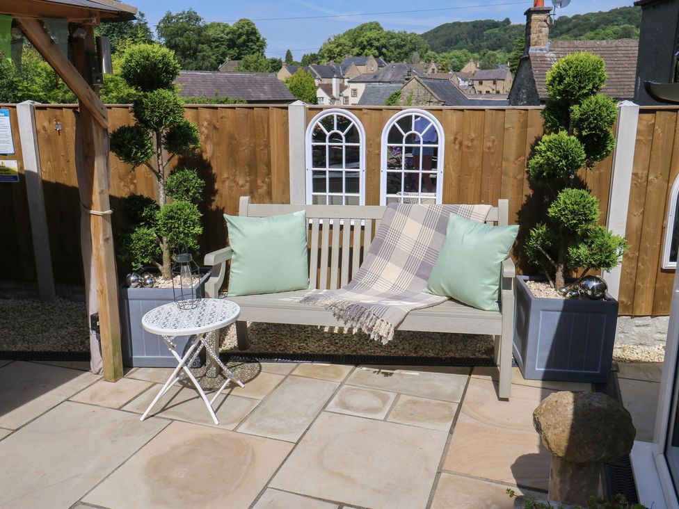 A garden with a bench, side table, and plants at Lydgate Cottage in Eyam