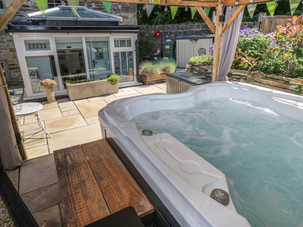 An outdoor area with a hot tub, table and chairs at Lydgate Cottage in Eyam