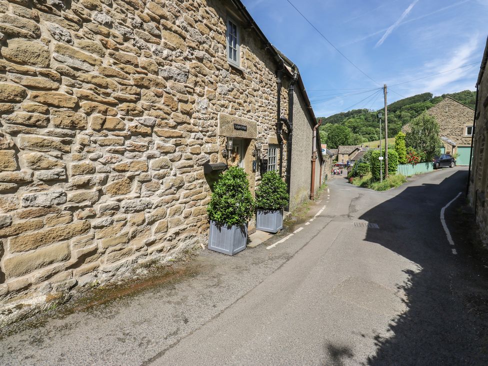 An outdoor view of a stone cottage and street at Lydgate Cottage Eyam