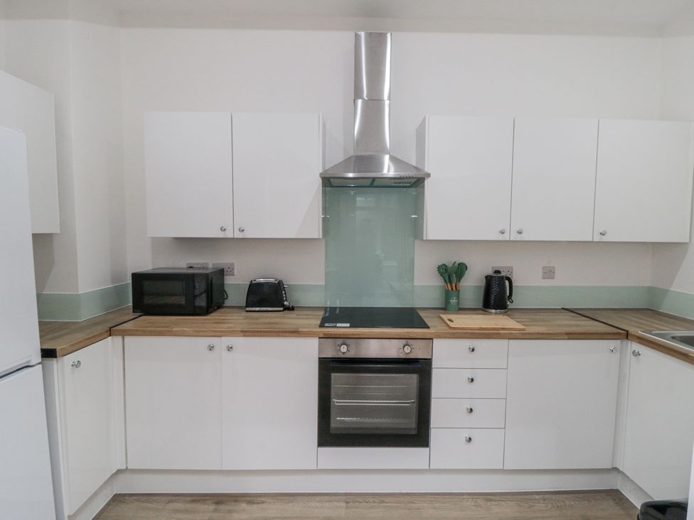 A kitchen with cabinets, a cooker, and appliances at Beachwalk Villa 1 in Whitby