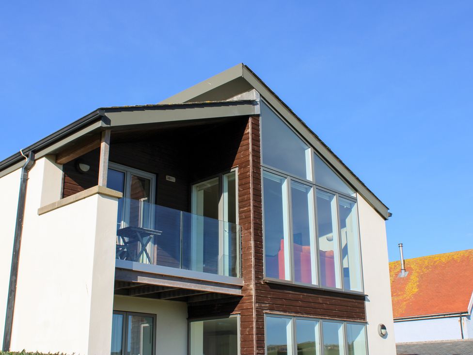 A house with a balcony and large windows at 10 Oceans Edge in Thurlestone