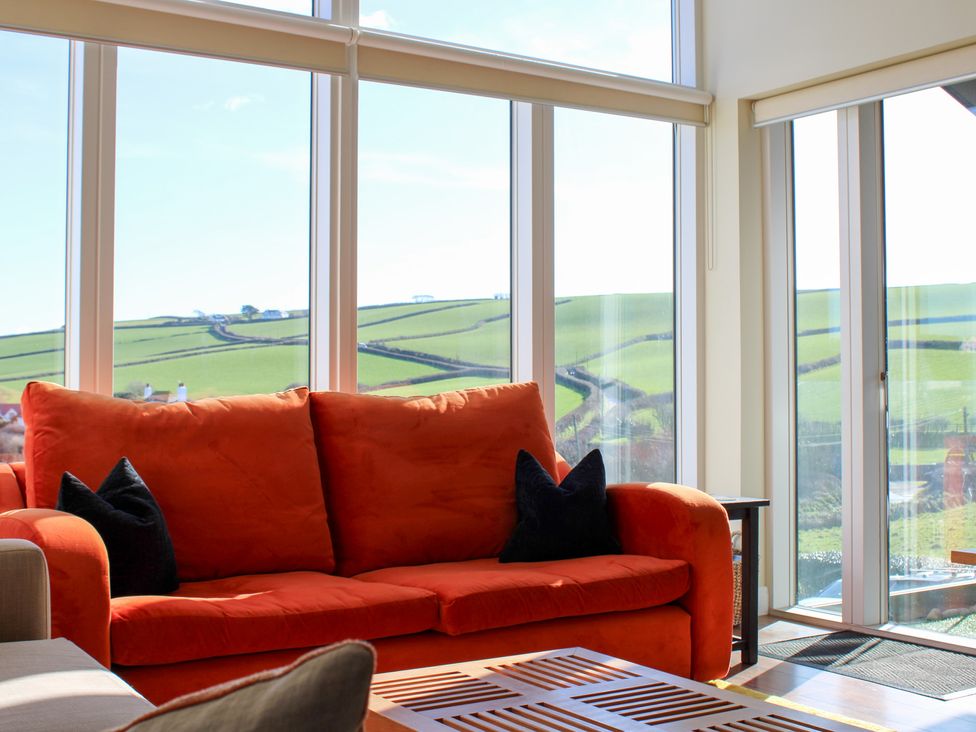 A living room with an orange couch and a coffee table at 10 Oceans Edge in Thurlestone