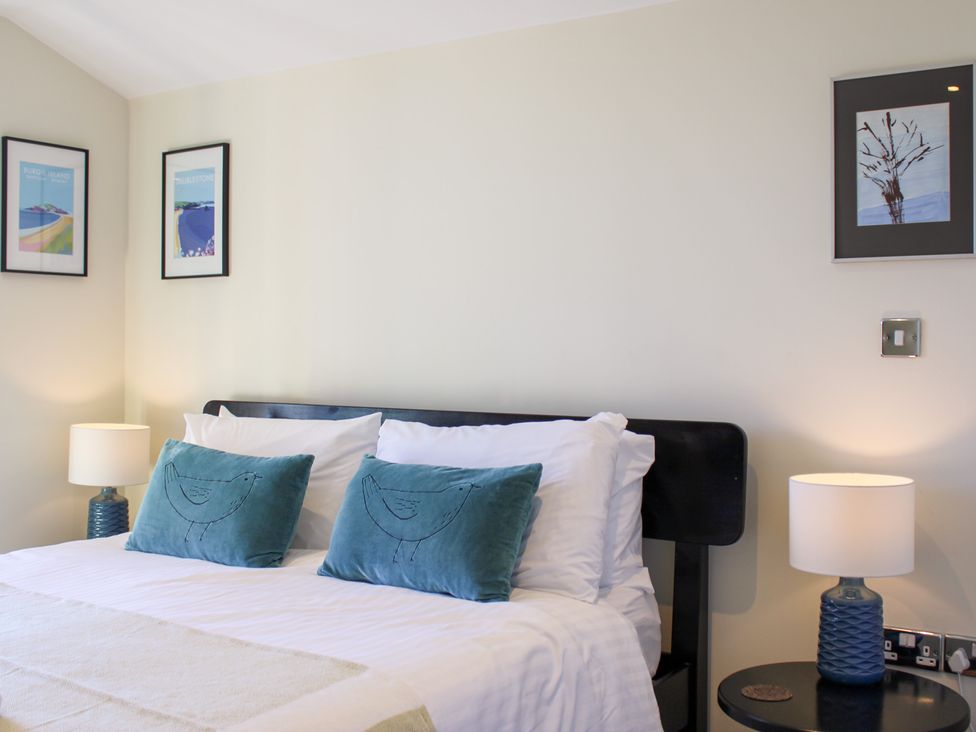 A bedroom with a bed and framed pictures at 10 Oceans Edge in Thurlestone