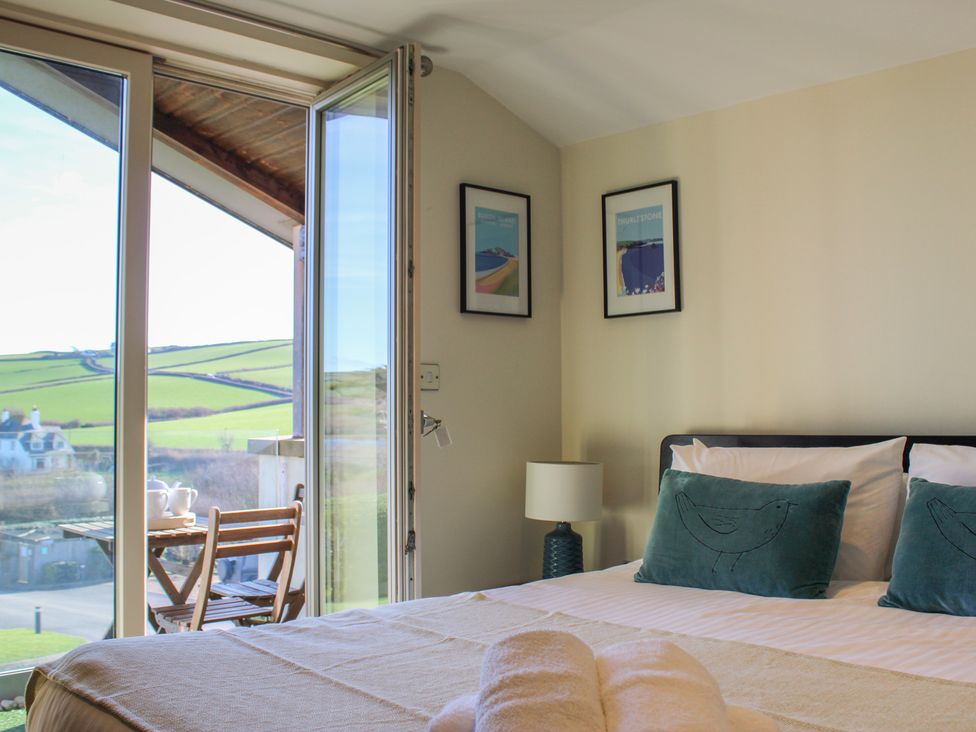A bedroom with a bed and a window overlooking the landscape at 10 Oceans Edge Thurlestone