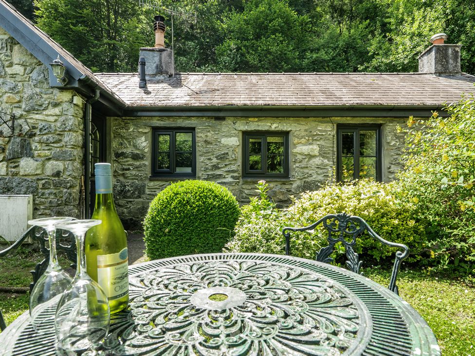 A table and chairs with wine and glasses at Tyn Y Ffynnon in Betws-Y-Coed
