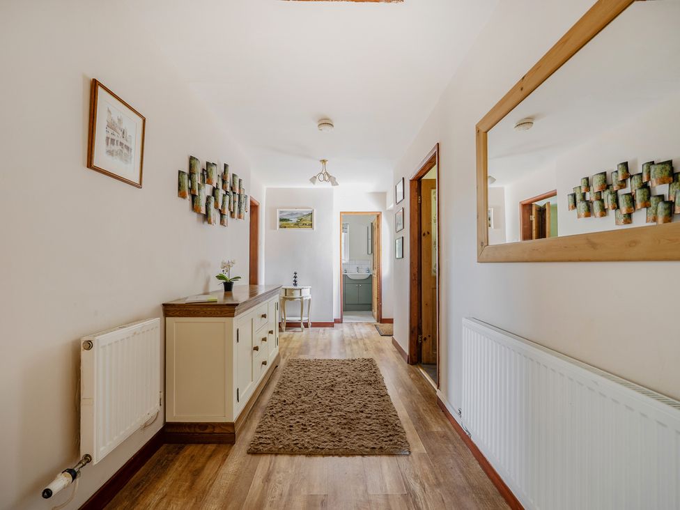 A hallway with a table, mirror, and wall decor at Tyn Y Ffynnon in Betws-Y-Coed
