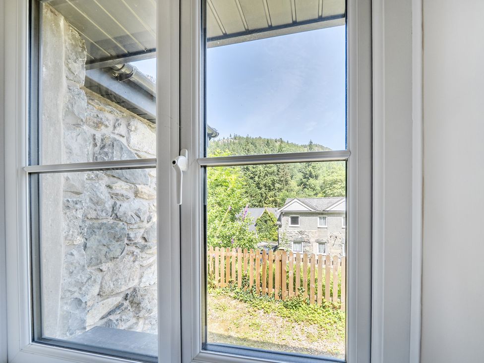 A view from a window showing a house and landscape at Tyn Y Ffynnon in Betws-Y-Coed