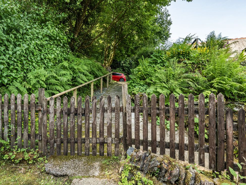 A pathway with a wooden fence and a car at Tyn Y Ffynnon in Betws-Y-Coed