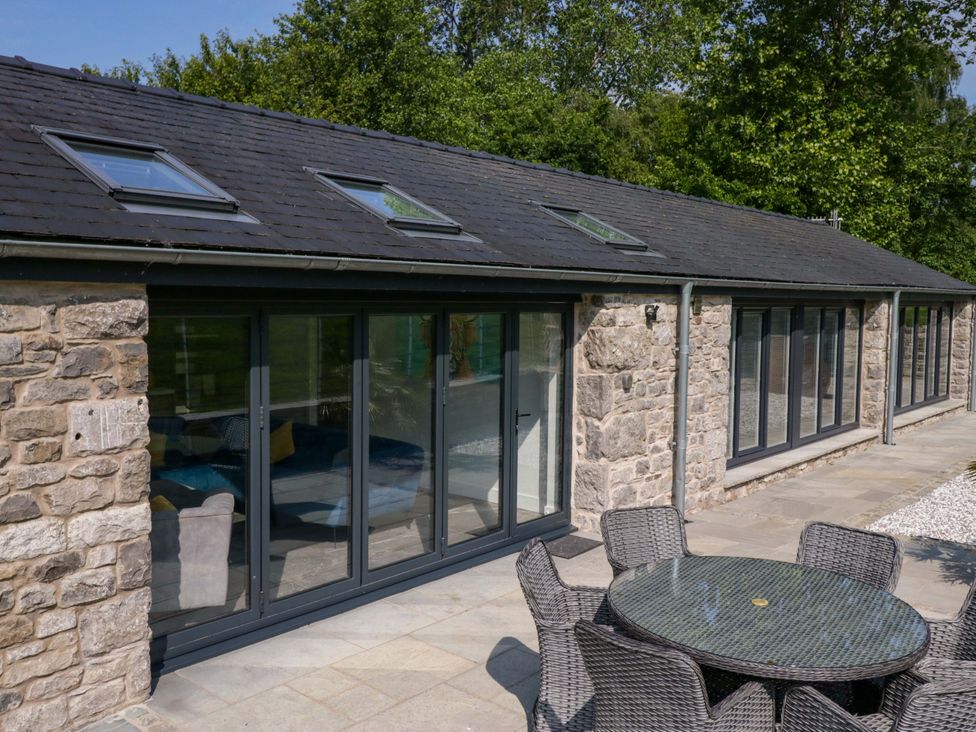 An outdoor area with a stone wall and glass doors at Limestone in Great Urswick