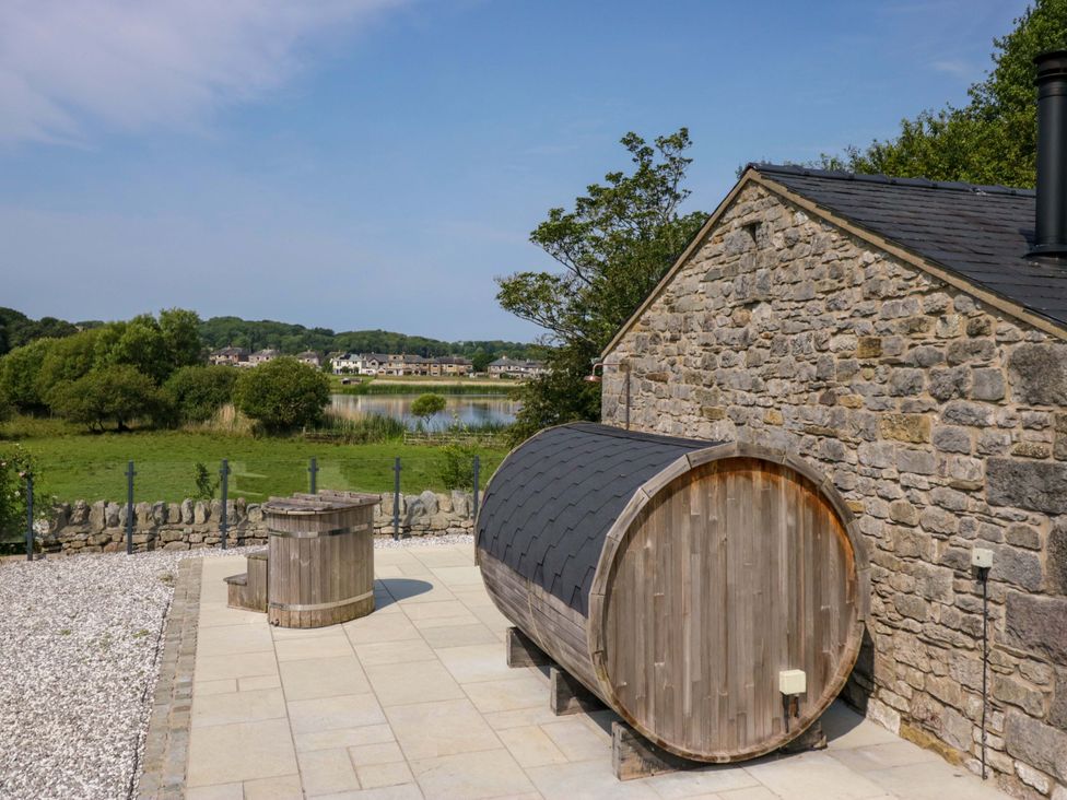 An outdoor area with a wooden barrel sauna and hot tub at Limestone in Great Urswick