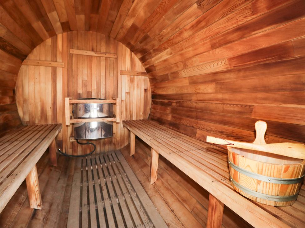 A sauna with wooden benches and a stove at Limestone in Great Urswick
