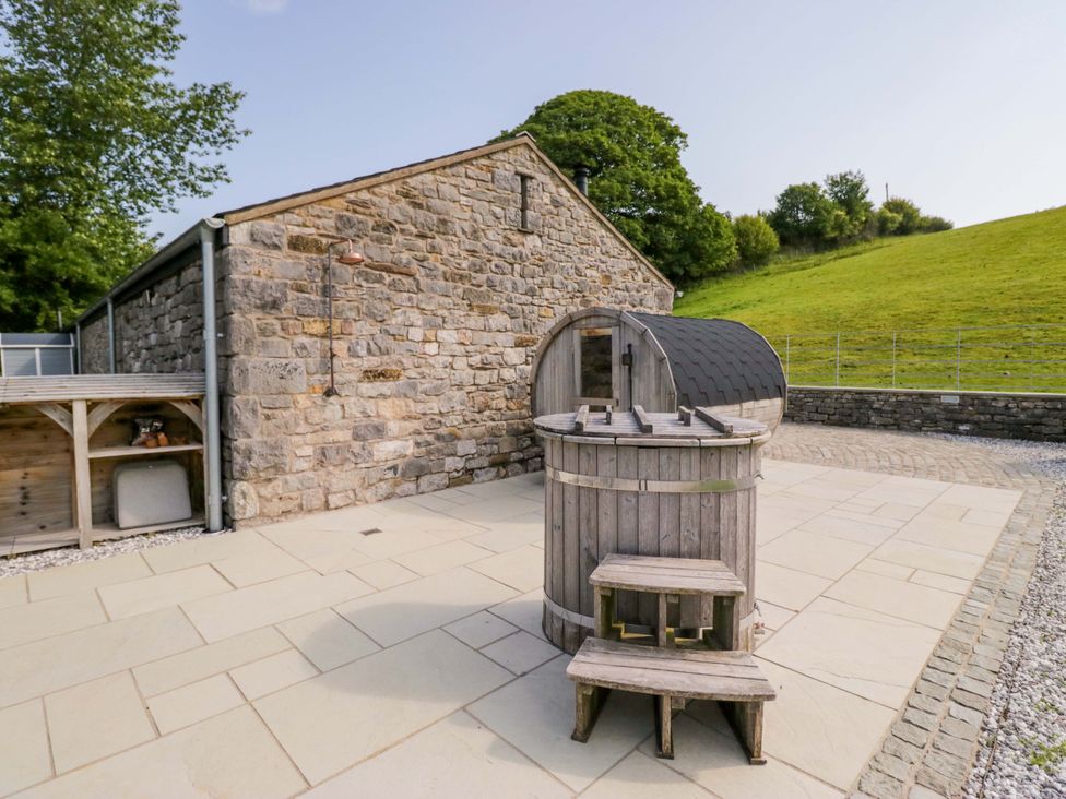 An outdoor area with a stone building and wooden hot tub at Limestone in Great Urswick