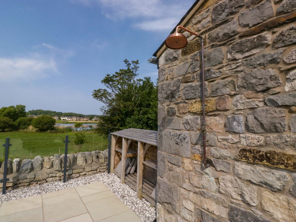 An outdoor shower next to a stone wall and shed at Limestone in Great Urswick