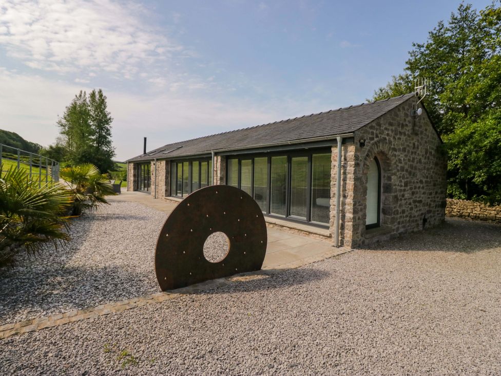 A stone building with large windows and a sculpture at Limestone in Great Urswick