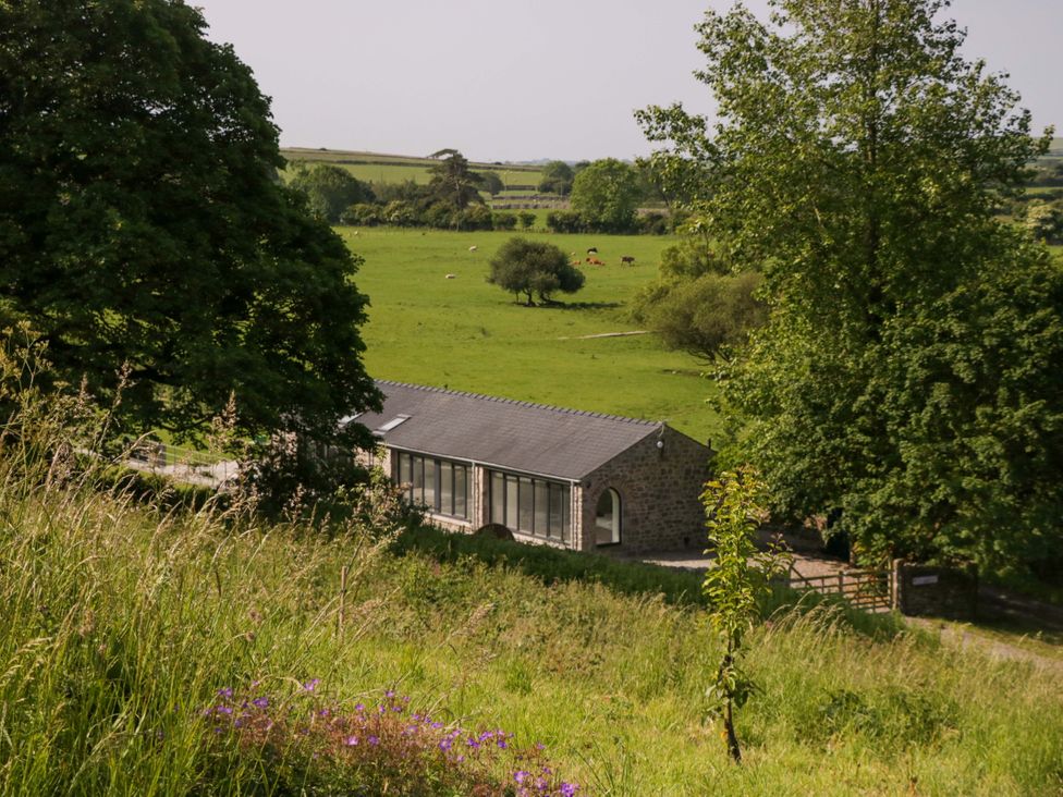 A view of a building surrounded by grass and trees at Limestone in Great Urswick