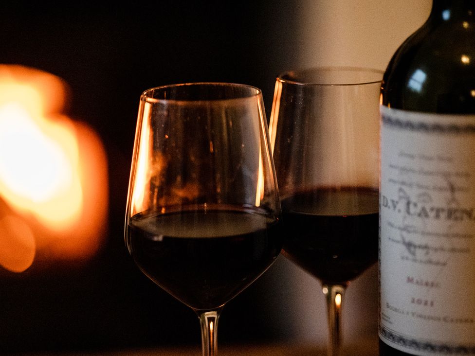 Two wine glasses with red wine and a bottle in front of a fireplace at Pendle View Luxury Apartment Giggleswick near Settle
