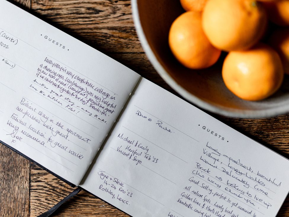 A guestbook with handwritten notes and a bowl of oranges at Pendle View Luxury Apartment Giggleswick near Settle
