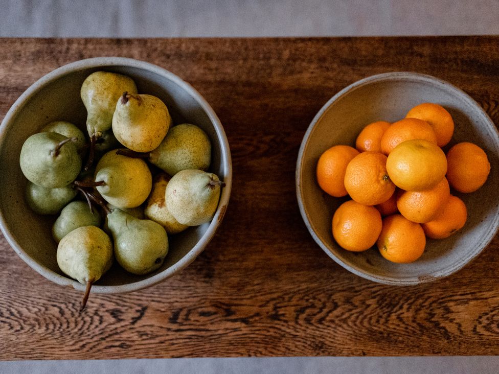 A bowl of pears and a bowl of oranges on a wooden table at Pendle View Luxury Apartment Giggleswick near Settle