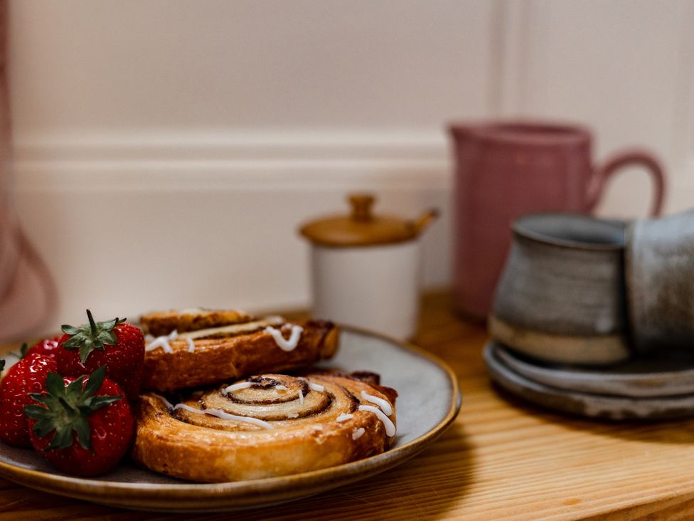 A plate with cinnamon rolls and strawberries in a kitchen