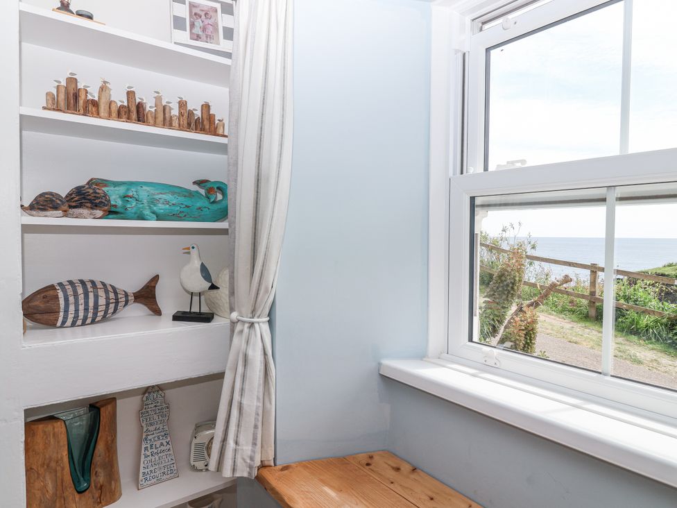 A room with a shelf and decorative items at 2 Cliff Cottages in West Portholland near Gorran Haven